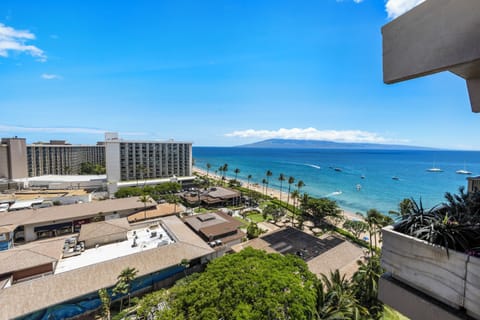 Oceanfront property with panoramic views of the sandy beach, turquoise waters, and distant island mountains under clear blue skies.