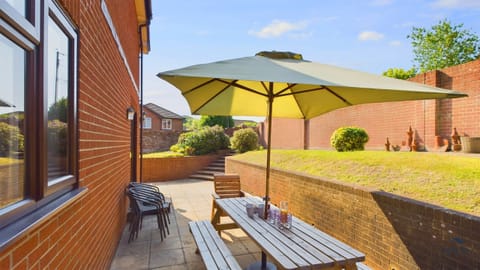 The private rear patio features a large dining set and parasol, ideal for summer holiday barbecues.