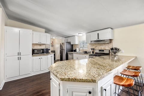 Bright kitchen with granite countertops, island seating, and full-size appliances
