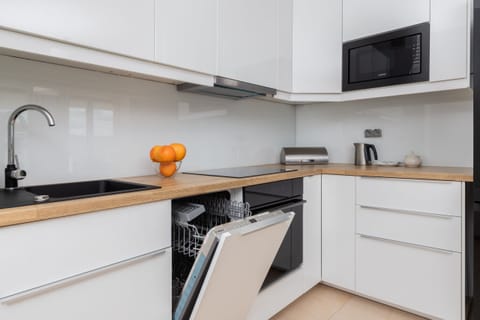 A contemporary open-plan kitchen equipped with white cabinets, a sleek countertop, and modern appliances.