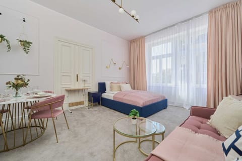 A bright and sophisticated living space with a blush pink sofa, golden accents, and a royal blue armchair, creating a luxurious atmosphere.