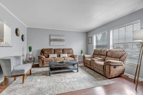 Main Floor Living Area with lots of natural light, reclining couches and large oversized wall mounted tv.