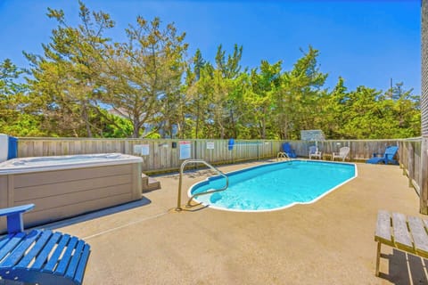 Inviting private pool oasis with hot tub and plenty of lounge seating, surrounded by natural landscaping and blue skies, perfect for warm summer days.