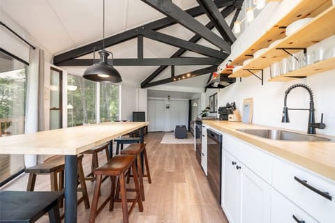 Open kitchen and dining area with sleek counters, modern shelving, and vaulted ceilings for an airy feel.