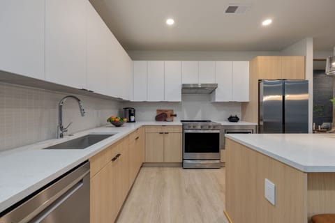 Fully equipped kitchen boasting stainless-steel appliances and an island offering bar seating. Kitchen fully stocked with all culinary essentials for ease and convenience.