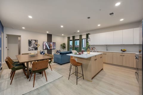 Spacious modern open-concept floor plan featuring the fully equipped kitchen, dining area, and designer furnished living room.