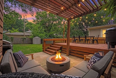 Beautiful backyard retreat featuring a cozy fire-pit lounge under a modern pergola, spacious deck, and lush fenced yard—perfect for gatherings and summer nights.