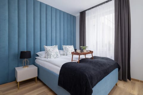 A cozy bedroom with a luxurious blue accent wall, a comfortable double bed, and soft lighting for a relaxing atmosphere.


