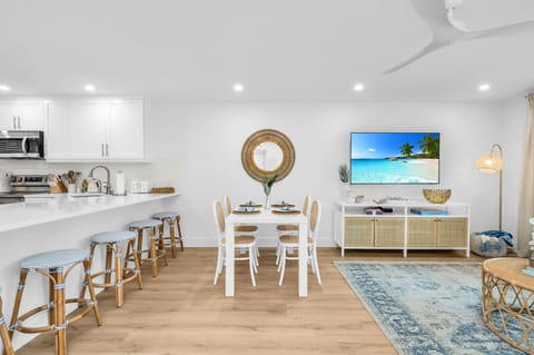 There are 5 sky-blue rattan bar stools at the impressively large quartz kitchen counter. The kitchen also has a kitchen nook with 2 upholstered rattan and cane benches, a modern contemporary white round table, and a decorative Fiddle tree.