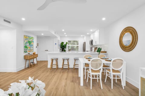 There are 5 sky-blue rattan bar stools at the impressively large quartz kitchen counter. The kitchen also has a kitchen nook with 2 upholstered rattan and cane benches, a modern contemporary white round table, and a decorative Fiddle tree