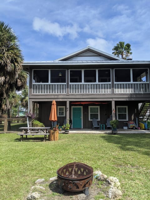 View from canal towards house. Fenced yard on left. Upstairs screened porch.