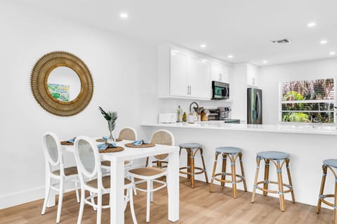 There are 5 sky-blue rattan bar stools at the impressively large quartz kitchen counter.