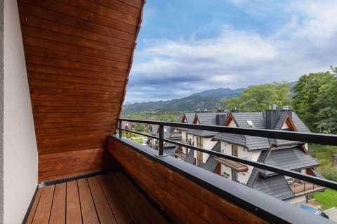 A private balcony with a wooden railing offering scenic views of the traditional highlander-style neighborhood.

