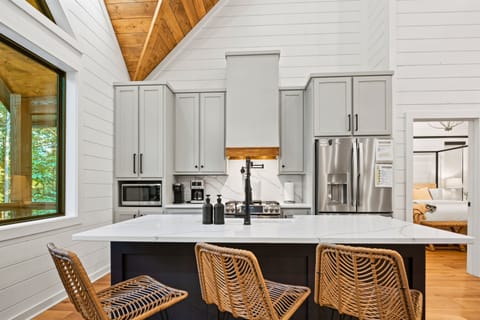 This modern kitchen is highlighted by an island with stylish wicker seating, surrounded by clean-lined cabinetry and state-of-the-art appliances.