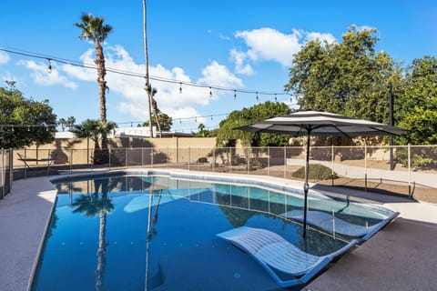 Private, heated pool with in-pool loungers and string lights.