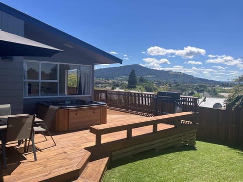 Elevated timber deck with spa pool and panoramic Rotorua hill views — ideal outdoor entertaining for holiday stays