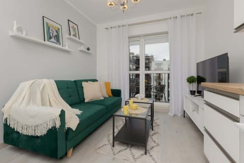A cozy living room with a green sofa, white accents, and a bright, open layout.

