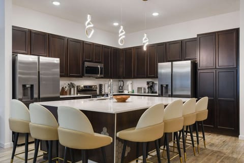 Luxury kitchen with dark wood cabinetry, sleek appliances, and a spacious island.