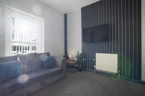 Lounge in a bright living room with comfortable sofas, soft lighting and tasteful coastal décor. Large windows fill the space with natural light, creating a welcoming setting to relax, catch up and enjoy quiet evenings together.