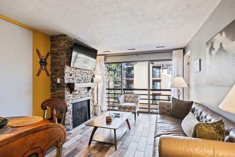 Inviting living room featuring a stone fireplace, cozy seating, and access to a private balcony.