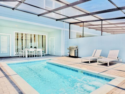Private screened pool deck with sparkling pool and sun loungers.
