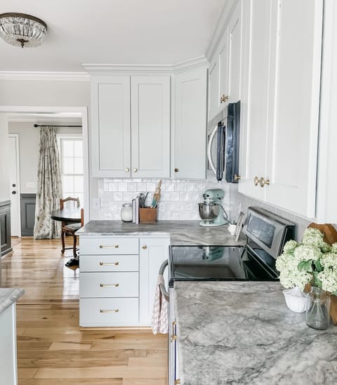 Bright and modern kitchen with ample storage, marble countertops, and charming details.