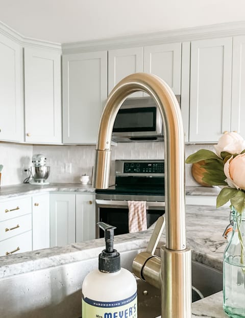 Stylish kitchen with a sleek gold faucet, marble counters, and elegant finishes.