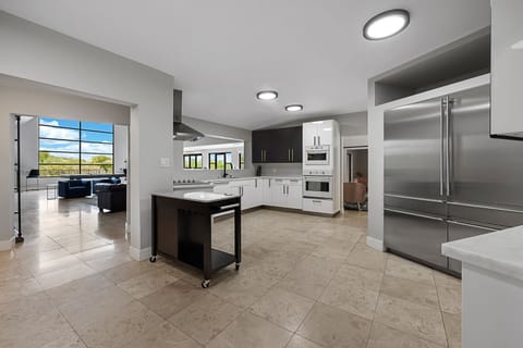 Modern kitchen w/ glass cooktop, built in oven, oversized fridge, & bar counter