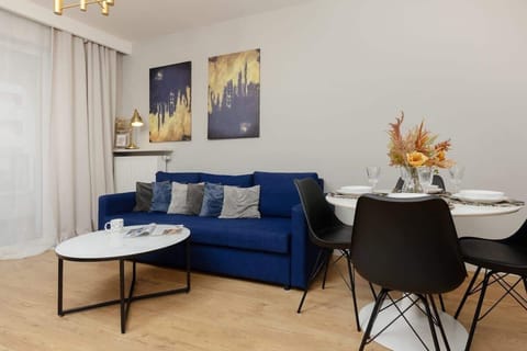 A bright, open living area featuring a comfortable blue sofa, a round coffee table, and a dining nook perfect for relaxing or enjoying a meal.

