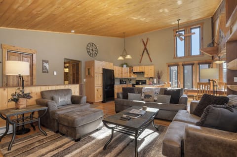 Relax in your cozy mountain retreat with rustic wood ceilings, plush sofas, and an open kitchen perfect for family gatherings.