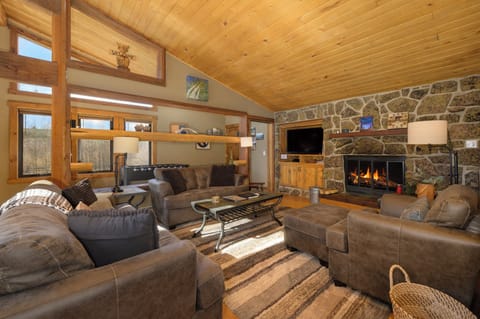 Sink into plush seating beside your crackling stone fireplace, where warm wood beams and mountain views create your perfect retreat.
