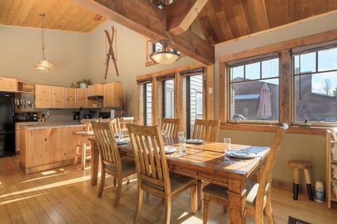 Gather around this rustic dining table where warm wood and natural light create your perfect mountain retreat atmosphere.