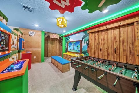 Enjoy a vibrant game room filled with colorful decor and playful elements, featuring a foosball table and arcade-style consoles. Bright lighting and dynamic wall art create the perfect atmosphere for unforgettable family fun.