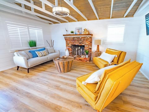 Bright living room with a rustic brick fireplace and modern yellow armchairs.