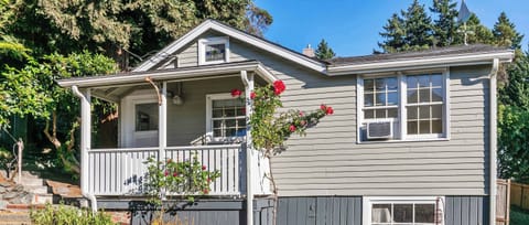 Charming cottage exterior with a welcoming front porch and blooming roses, creating a warm and inviting first impression.