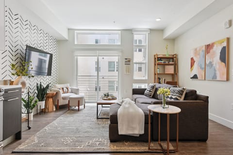 Sun-drenched open-plan living area with floor-to-ceiling windows, comfortable sofa, and designer finishes at EcoLoft Retreat.