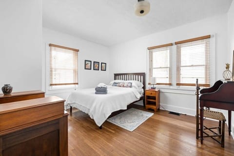 A queen bed paired with a bedside table, enhanced by wall-mounted frames, and complemented with a dresser for both convenience and a touch of style.