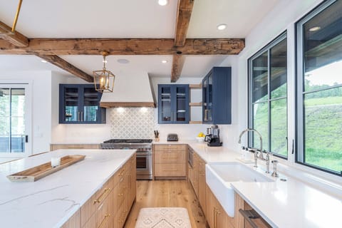 This modern kitchen, a chef's dream, boasts a farmhouse sink, large island with bar seating, pantry, stainless steel appliances, and luxurious quartz countertops, creating a stunning and functional culinary space.