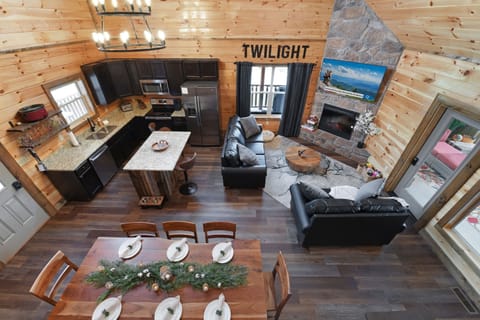 Open-concept rustic cabin living area with stone fireplace and modern kitchen