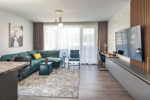 Spacious open living room with HD Smart TV, dedicated workspace and balcony. The property has a dedicated parking and access to playground