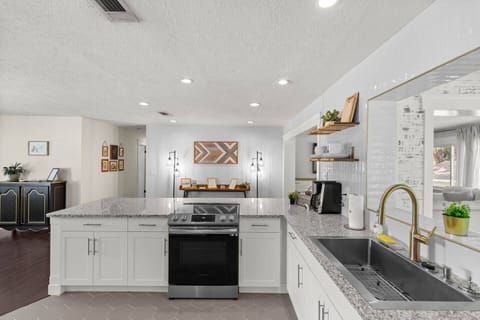 A modern, open-concept kitchen featuring an island with an electric range and granite countertops,