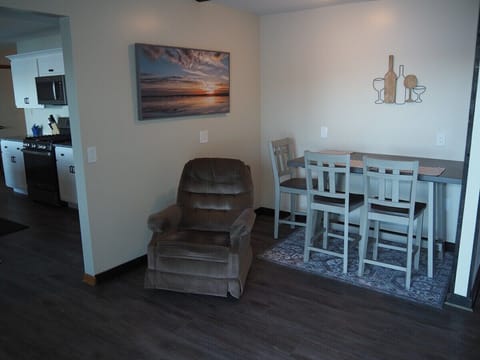 DINING AREA: In-between the kitchen and the living room is a small dining area and cozy chair that's in front of the television.