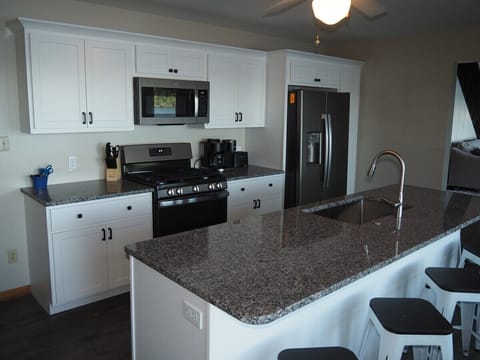 KITCHEN: Newly remodeled and features a gas stove and stovetop, refrigerator, microwave oven, dishwasher, Keurig coffee maker, toaster, island with sink, barstools, lots of counter space and cabinets, and a good supply of cooking & dining utensils.