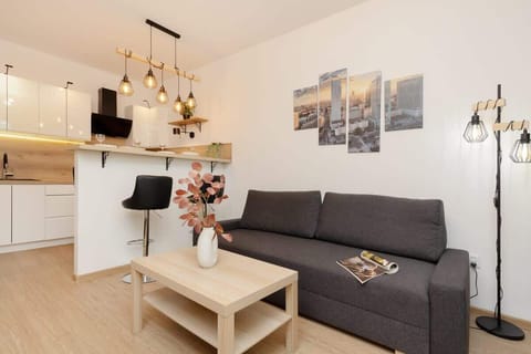 A stylish living room with a gray sofa, wooden coffee table, and warm pendant lighting creating a cozy atmosphere.
