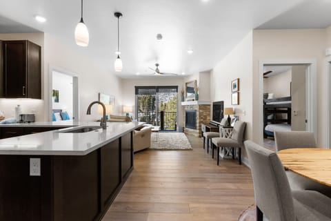 Your modern open-concept haven features sleek kitchen with quartz counters flowing into cozy living space with fireplace and mountain views.
