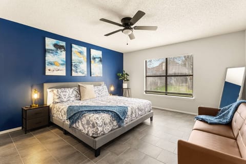 Spacious primary bedroom with king bed, cozy seating, and large window overlooking the backyard.