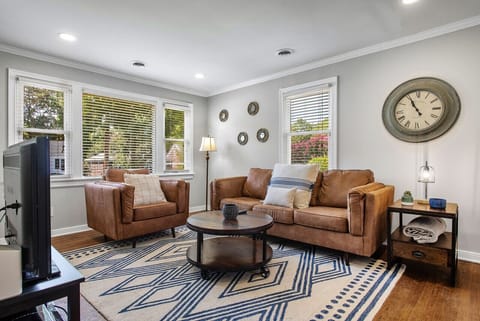 Spacious and modern living area with abundant natural light, a flat‑screen Roku TV, cozy couch and armchair.