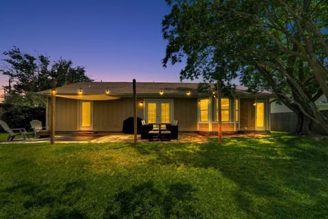 backyard with sun shade covered patio, patio lounge set, grill, and fire pit.
