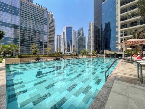 This modern urban pool is surrounded by tall glass buildings and features clear water, stylish tiles, and shaded loungers. It’s the perfect city escape in Dubai.