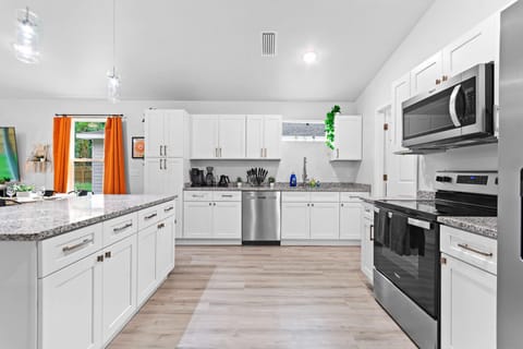 Sleek white kitchen with stainless steel appliances and bright details.